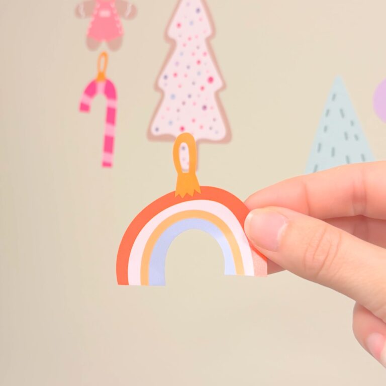 Holly jolly wallstickers - en hand som håller en av pyntelement formade som en regnbåge