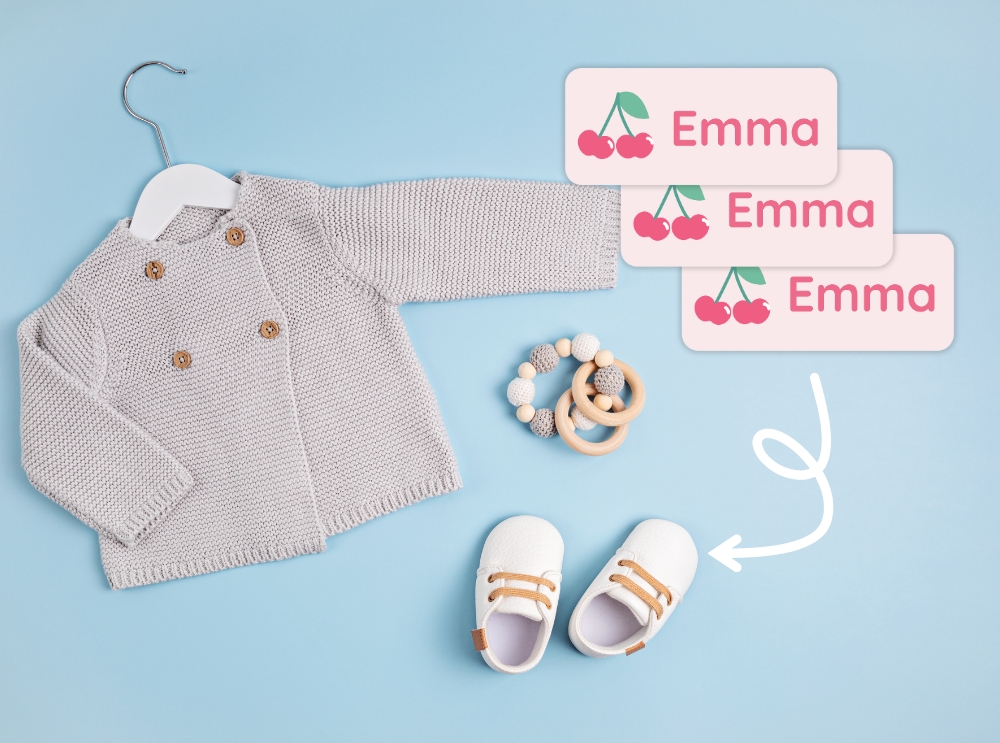 Babykläder och skor med rosa namnlappar med körsbär och namnet emma