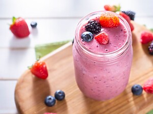 Närbild av en rosa uppfriskande smoothie toppad med färska bär