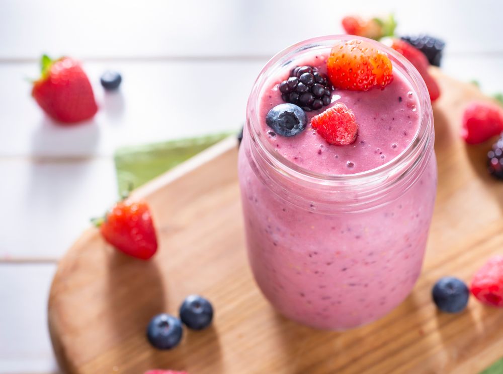 Närbild av en rosa uppfriskande smoothie toppad med färska bär