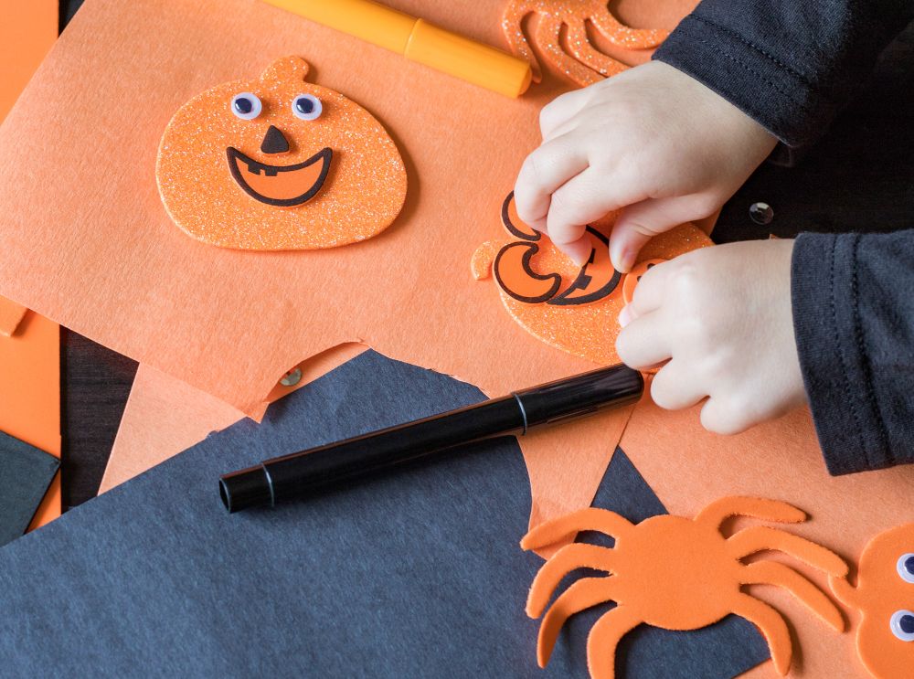 Barn som pysslar pumpadekorationer med orange och svart papper