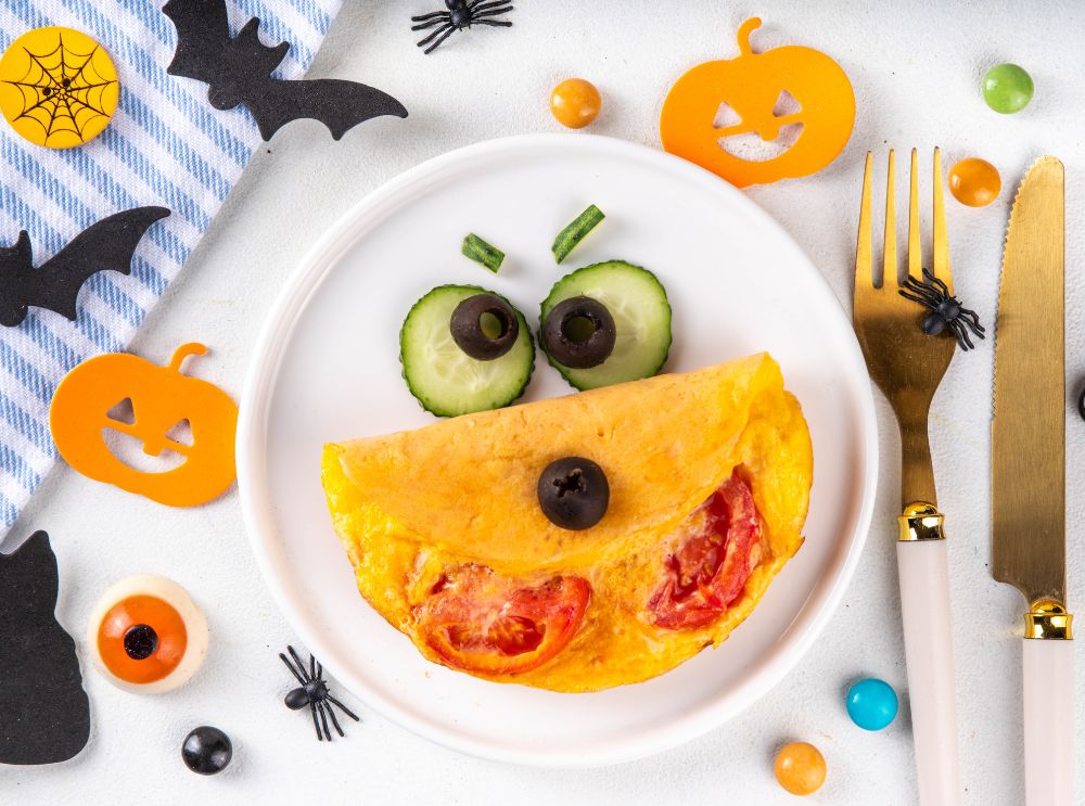 Halloweenomelett dekorerad med gurka och oliver som ett roligt ansikte