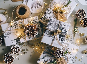 Festlig flat lay av inslagna julklappar med kottar, snöre och varma tomtebloss