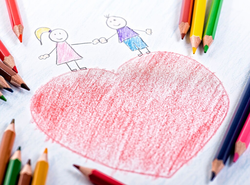 Alla hjärtans dag med barn: enkla pyssel och söta familjefavoriter 1 Barnteckning av ett stort rött hjärta med två streckgubbar som håller varandra i handen, omgiven av färgpennor.