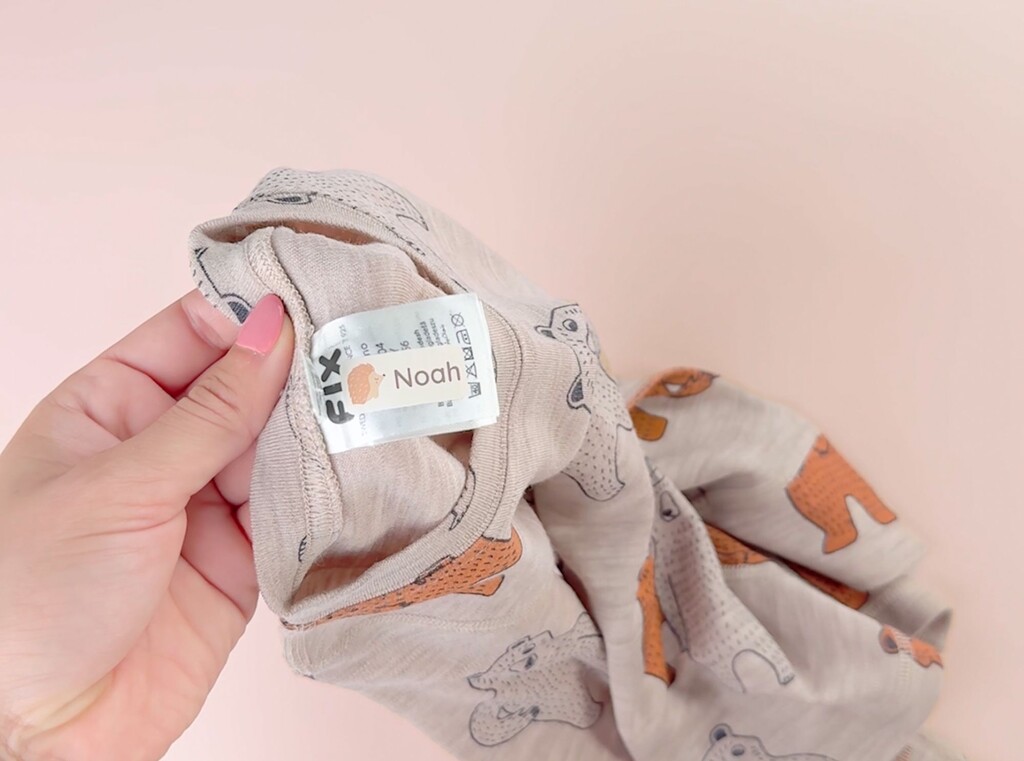 Närbild av en personlig namnlapp med namnet Noah fäst på tvättrådsetiketten i ett barns beiga plagg