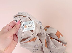 Närbild av en personlig namnlapp med namnet Noah fäst på tvättrådsetiketten i ett barns beiga plagg