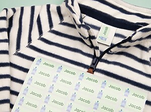Ark med gröna namnlappar med flodhästdesign placerat på en randig barntröja