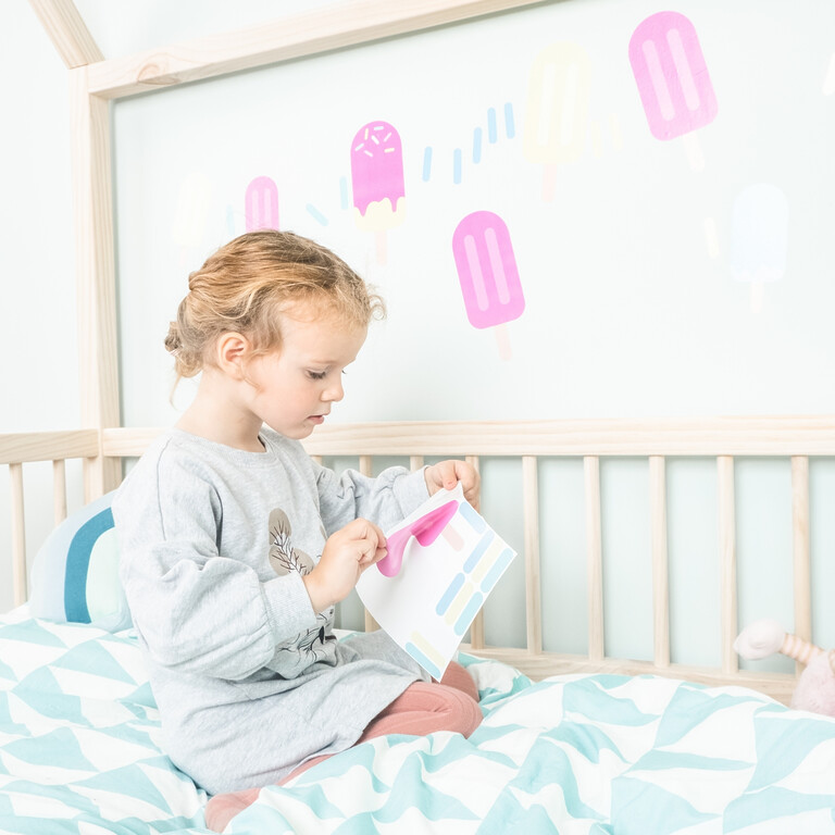 Flicka som fäster glass-wallstickers på vägg