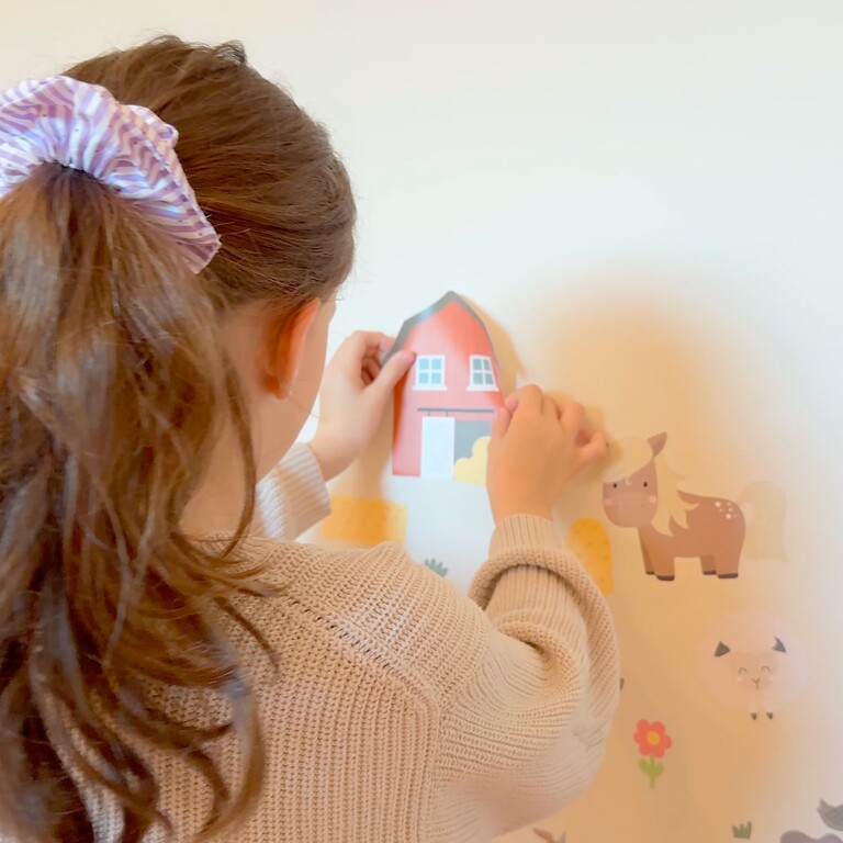 Flicka som fäster wallstickers på vägg