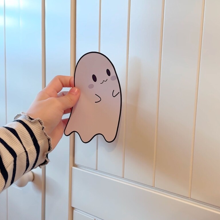 Barn som fäster spöke-wallsticker på ett skåp