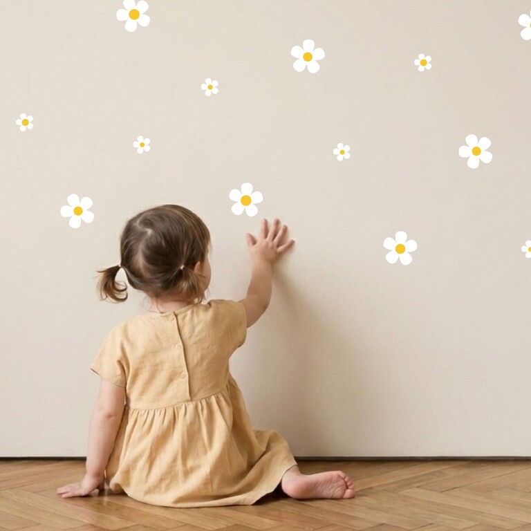 Daisy (vit) wallstickers som fästs på väggen av en hand